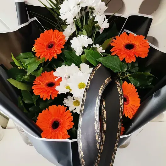 Buket narandžastih gerbera i belih cvetova sa trakom