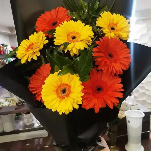 Buket žutih i narandžastih gerbera u crnom papiru