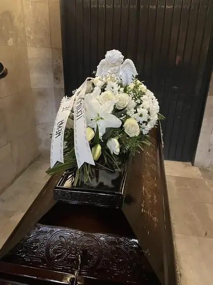 Suza od belog cveća sa anđelom na kovčegu