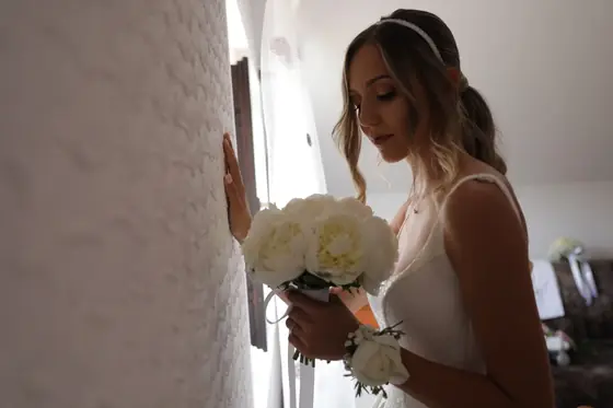 Mlada sa bidermajerom od belih ruža uz zid