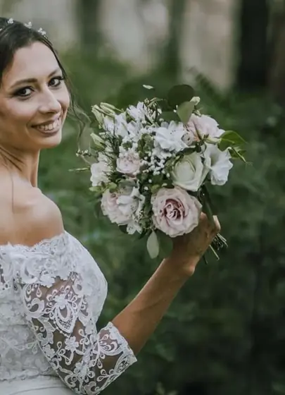 Mlada u čipkanoj venčanici sa bidermajerom od nežnih ružičastih ruža