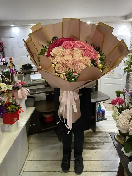 Buket ružičastih ruža u peskastom papiru sa roze trakom