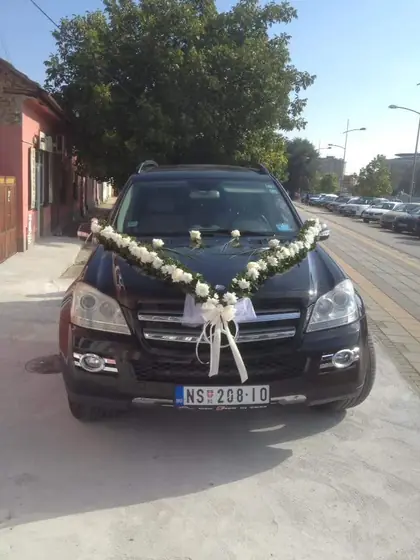 Ukras od belog cveća i mašne na crnom automobilu