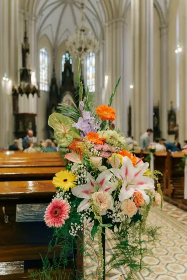 Aranžman od gerbera i ljiljana uz klupe u crkvi