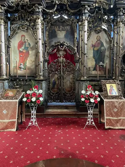 Dva aranžmana crvenog cveća ispred ikonostasa