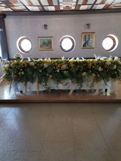 Mladenački sto ukrašen narandžastim i belim cvećem